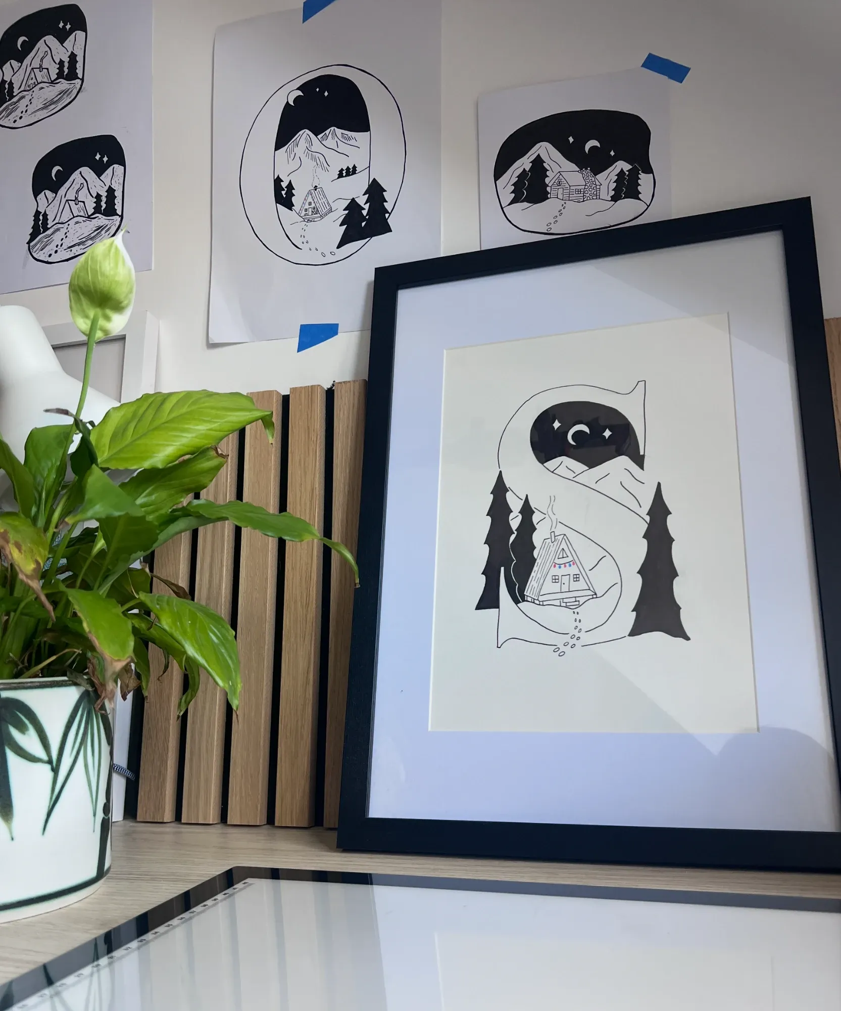 A framed letter S drawing with an A-frame cabin, in Lydia's studio